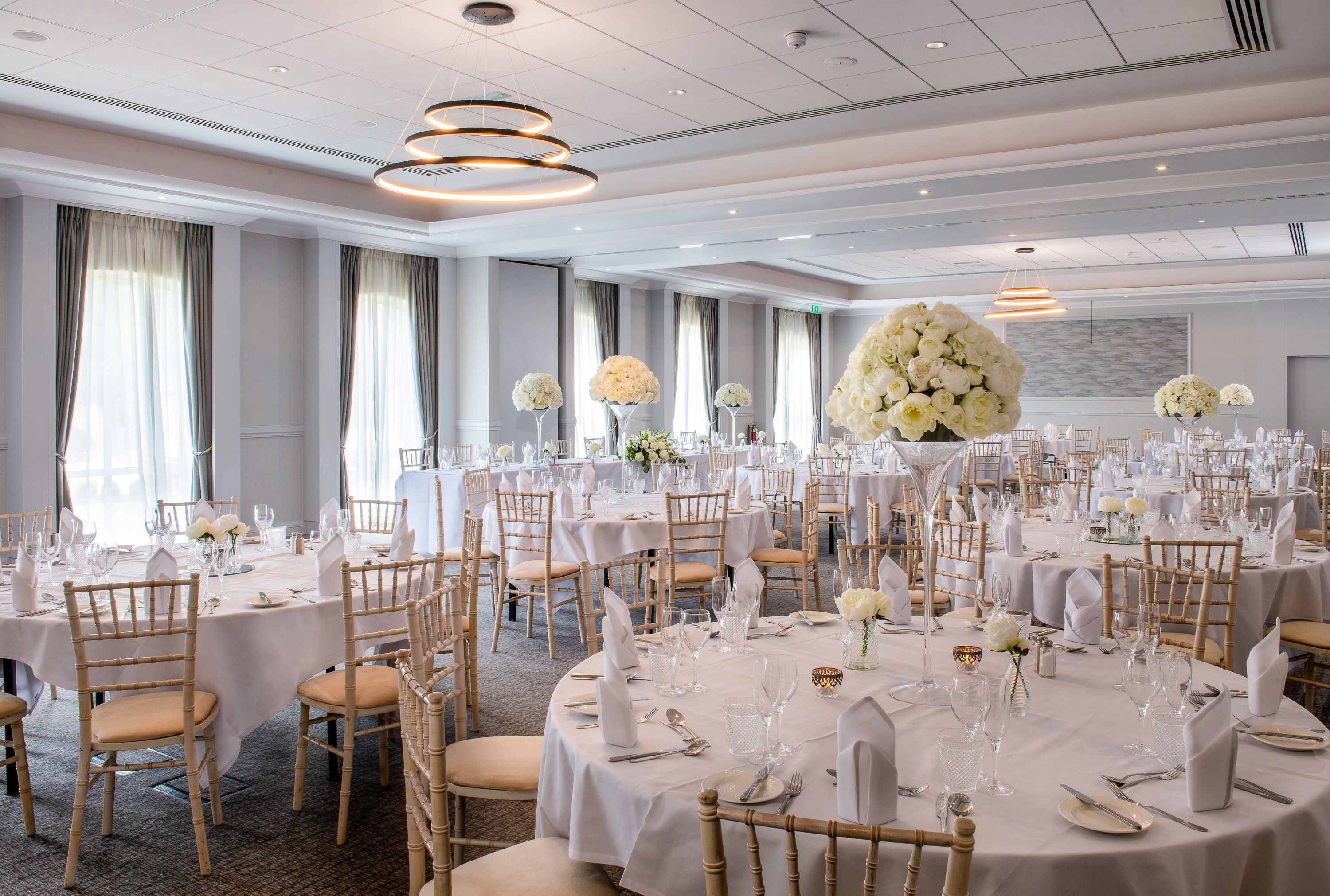 function room set up for wedding with large round tables and flower centre pieces