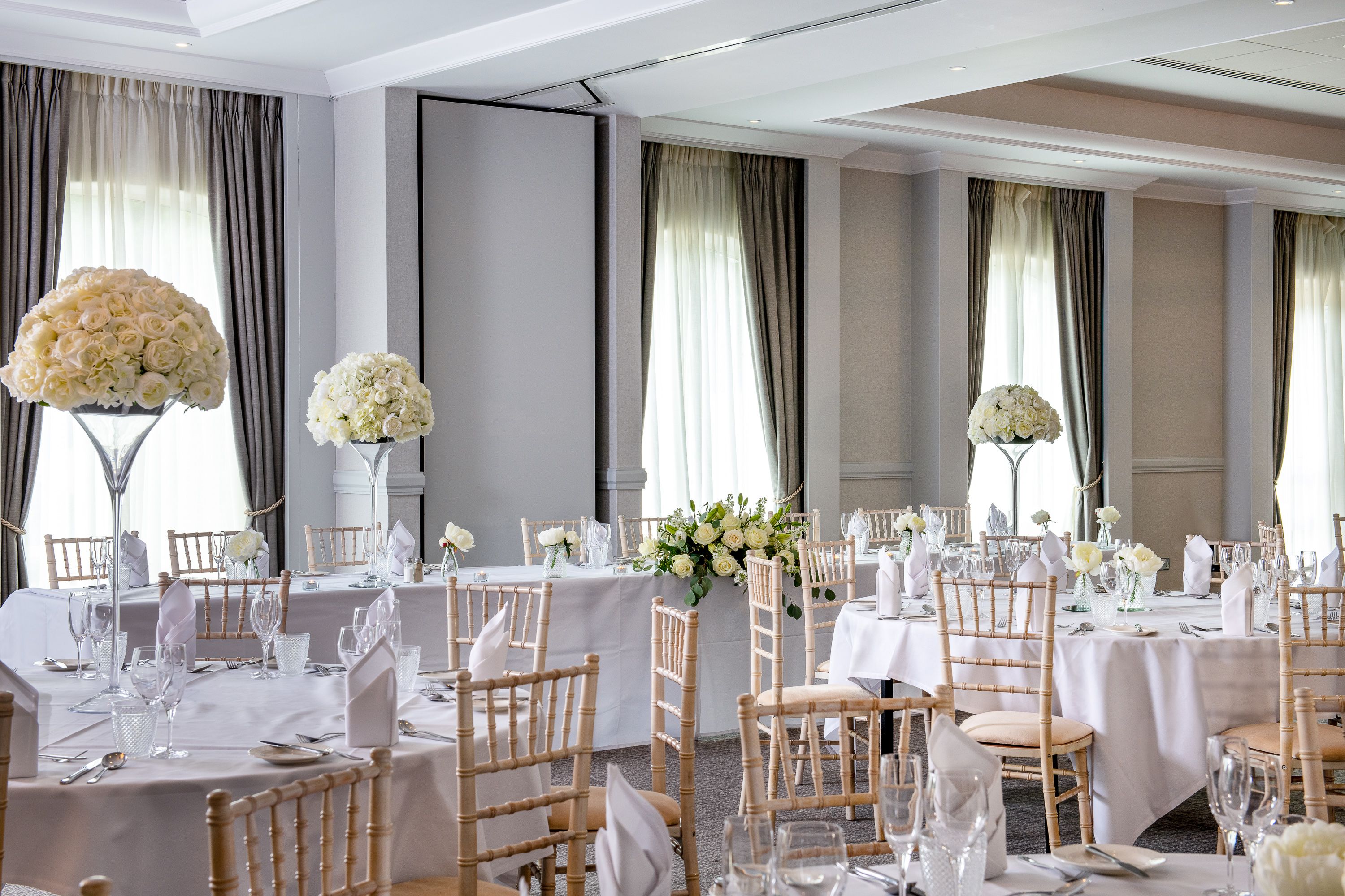 function room set up for wedding with large round tables and flower centre pieces