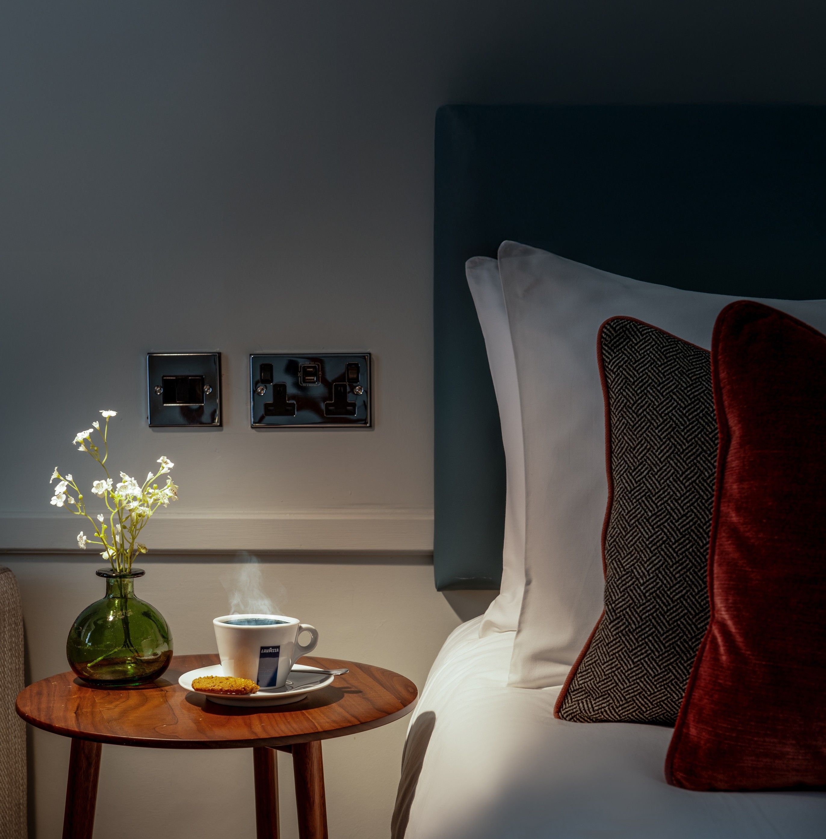 Close up of bedroom bed side table, with flowers and a cup of tea